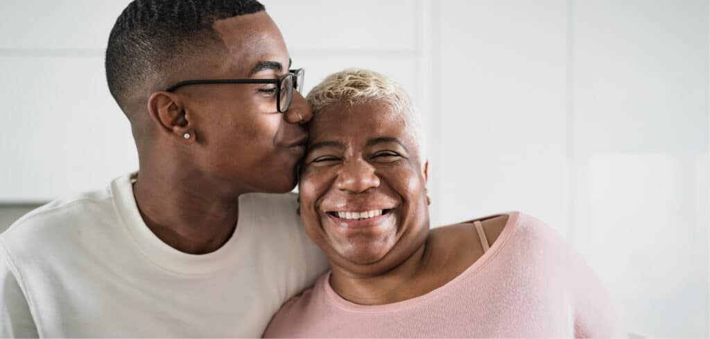 Young man kissing his mom on the cheek after she received dental implants in Spring, TX
